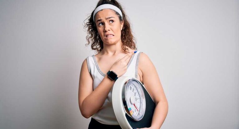 הטעות הנפוצה ביותר במהלך דיאטה שעלולה לעלות לכם ביוקר - בתמונה אישה אוחזת משקל ועל פניה הבעת חוסר שביעות רצון