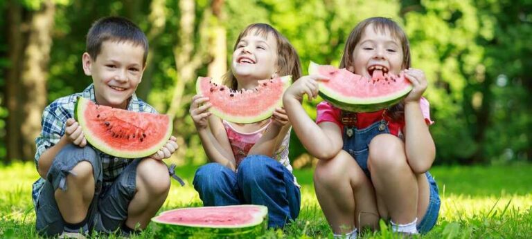 איך לשפר את הביטחון העצמי של ילדים באמצעות תזונה? - בתמונה ילדים אוכלים אבטיחים בפארק