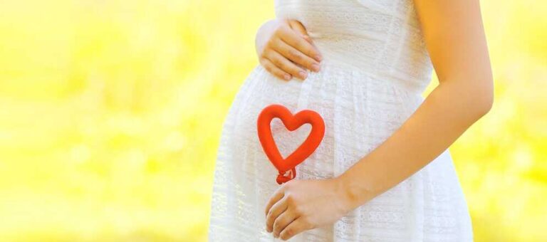 מה באמת אפשר לעשות כדי להקטין סיכון לאוטיזם? - בתמונה אישה בהריון אוחזת לב אדום בידה