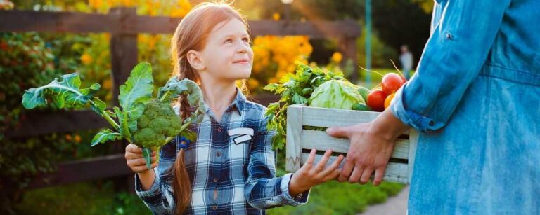 ילדה בטבע מחזיקה ירקות רבים